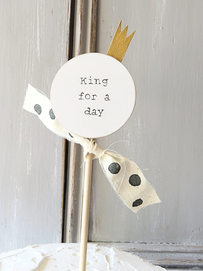 wooden circle shaped cake topper with hand painted message, gold painted crown detail and custom ribbon