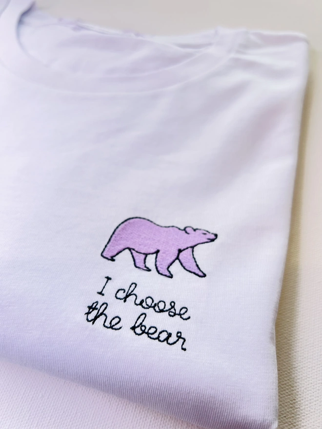     White T-shirt embroidered with lilac bear motif and the words “I choose the bear”