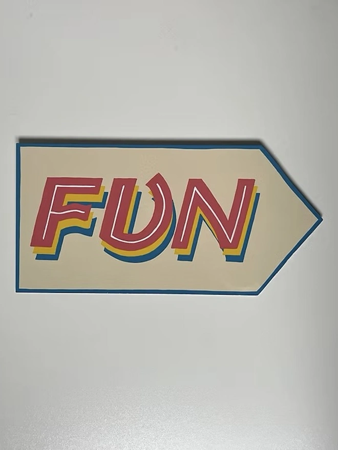 'Fun' Colourful Arrow Sign, a colourful sign hanging on a plain white wall. 