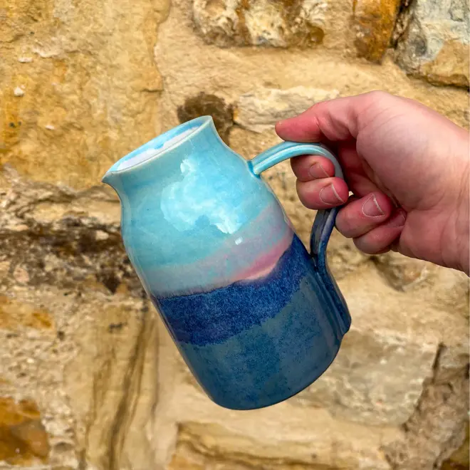 Landscape Small Jug, a colourful jug being poured against a brick wall. 