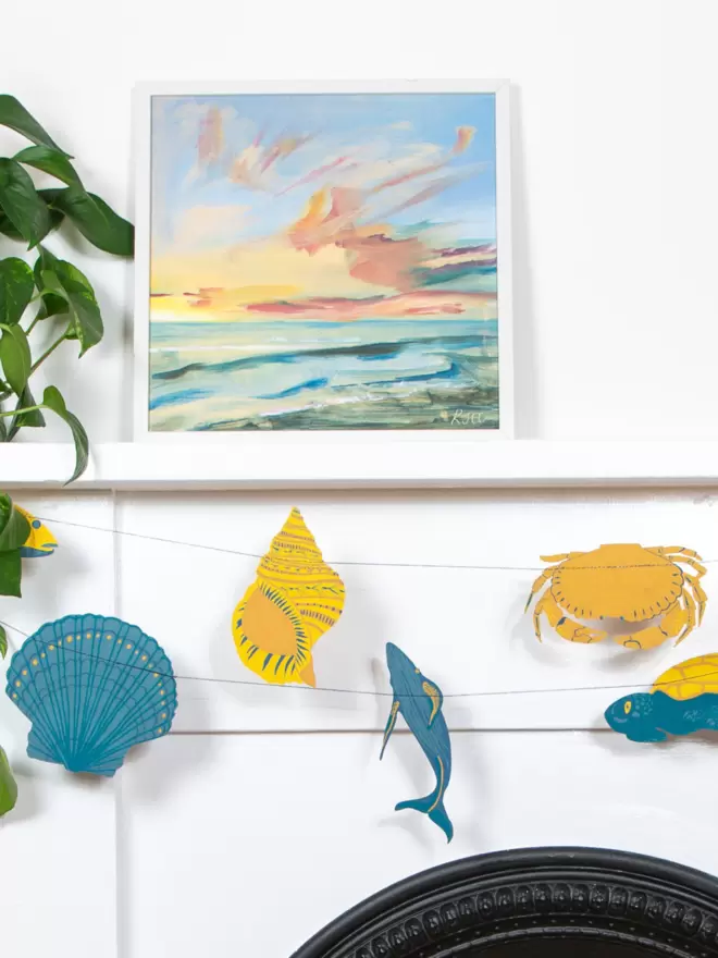 Garland hanging over fireplace with yellow and blue sea shells and fish decorations