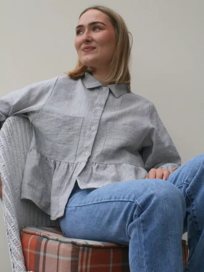 Peplum blouse in blue stripe, seated front view.