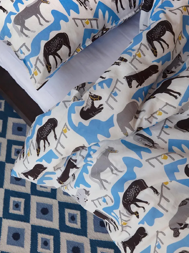 Horse Ranch Duvet Cover And Pillowcase, a blue horse themed set of a duvet cover and pillowcase in a bedroom. 
