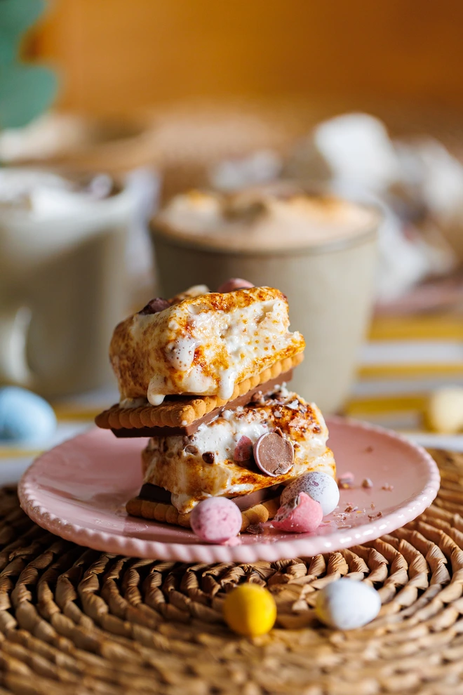 Mini Eggs Jumbo Marshmallows toasted and stacked between chocolate biscuits on a pink plate and wicker place mat
