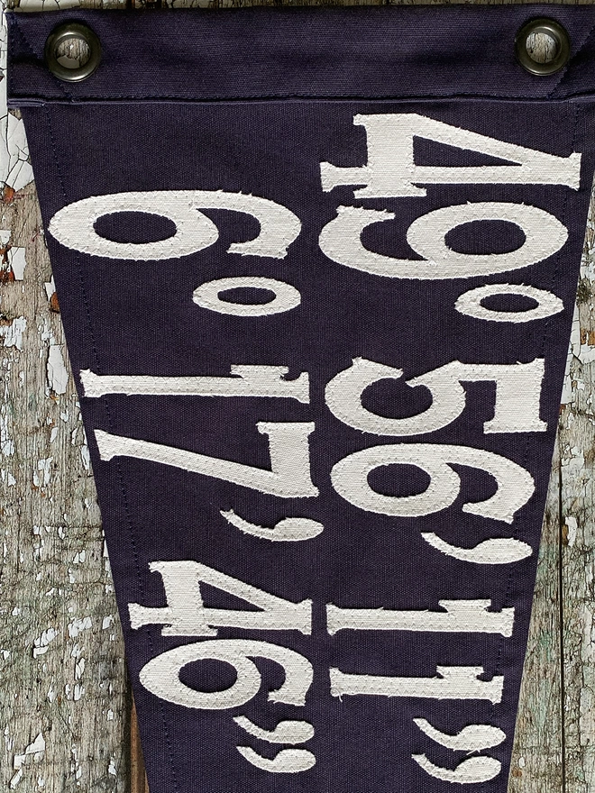 Detail of ivory canvas numbers on a navy pennant flag