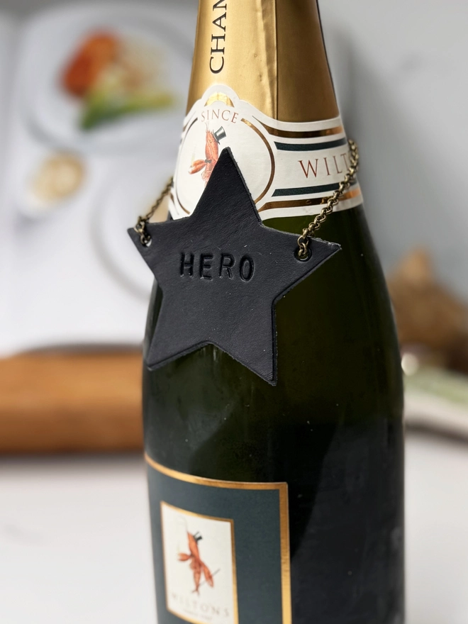 Navy blue leather star bottle tag with Hero stamped on it.