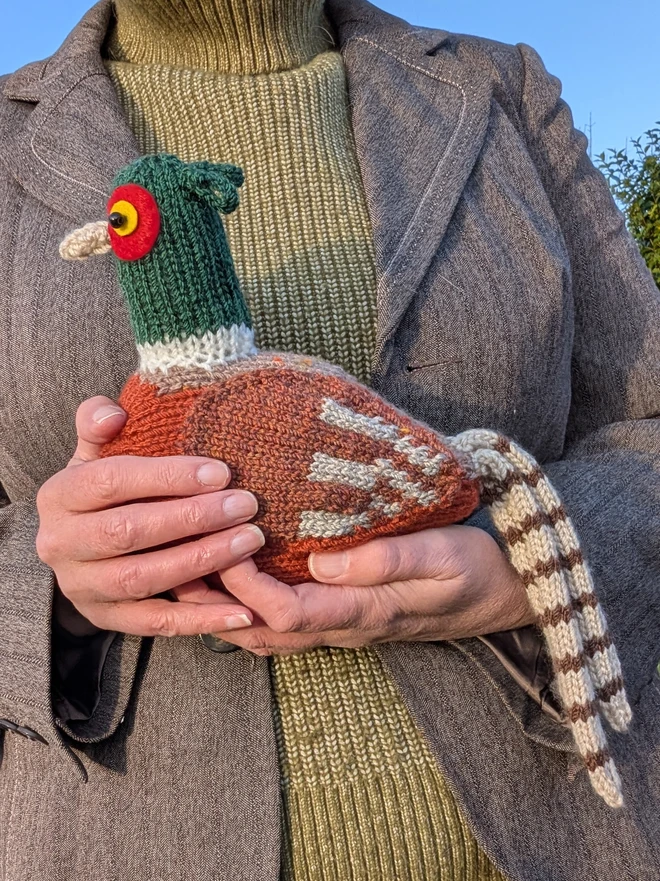 a cuddly knitted pheasant being given a cuddle