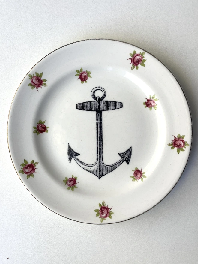 vintage plate with an ornate border, with a printed vintage illustration of an ship's anchor in the middle 