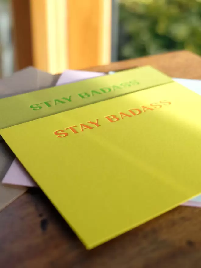 Bright yellow notecard with red ink wording 'Stay Badass'.