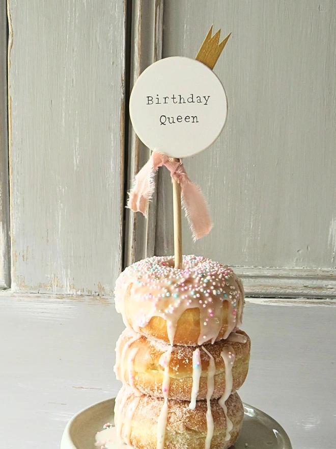 white wooden cake topper with hand painted message, gold painted crown detail and custom ribbon