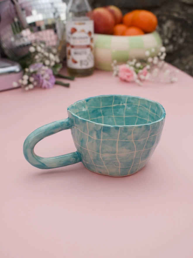 Swimming pool design on a stoneware handmade pottery mug in a bright turquoise blue grid pattern