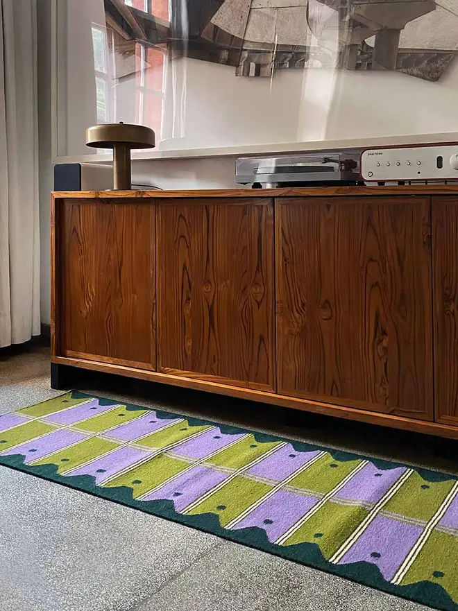 Ladder Flatweave Runner Rug, a colourful rug sitting in a living room. It is accompanied by other household items. 