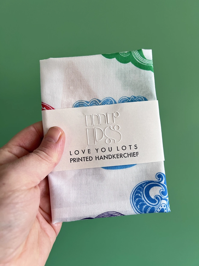 A Mr.PS Love You Lots Multicoloured Printed Handkerchief in packet held against a green background