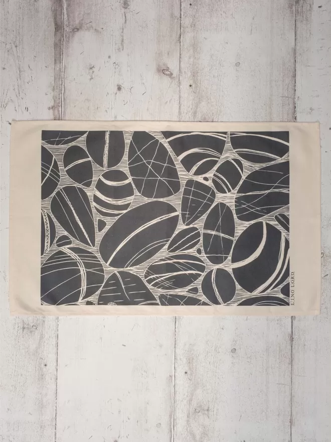 Picture of a tea towel with an image of pebbles, taken from an original lino print