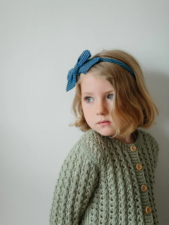 Little Girl wearing a blue gingham Alice Band with bow