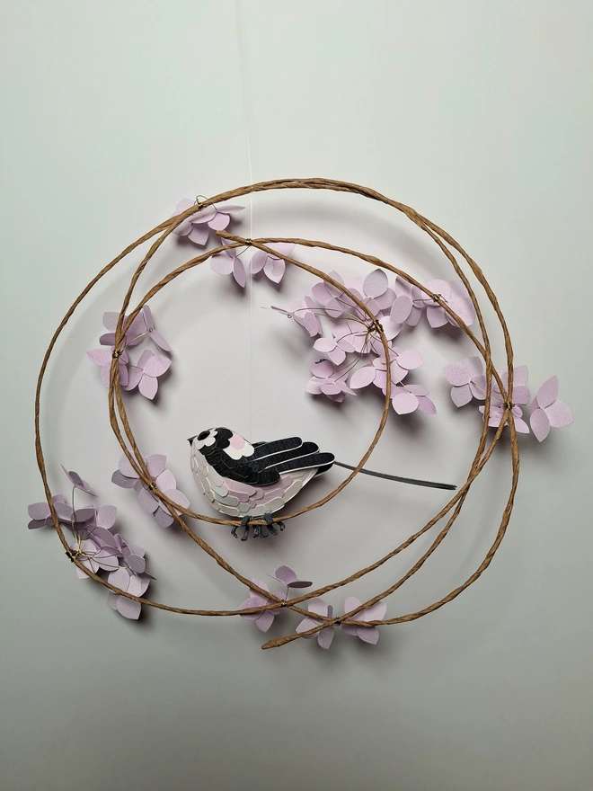 back view of a long tailed tit perched on a floral wreath