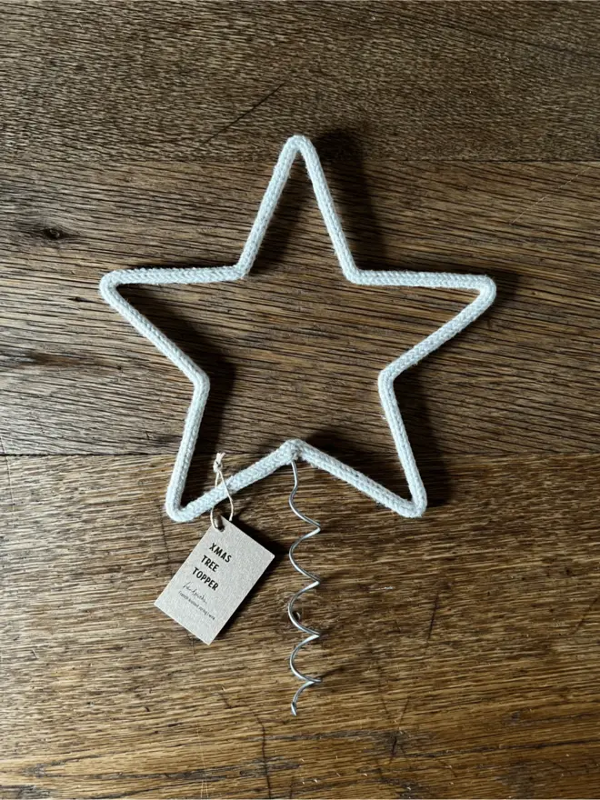 A large sized string wrapped wire star with coil and label on an oak table