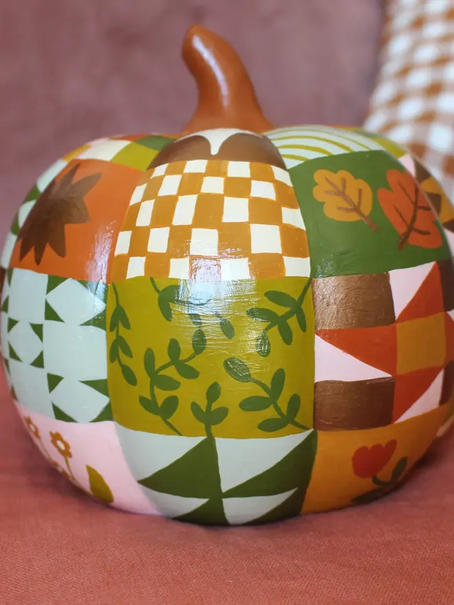 hand-painted woodland ceramic pumpkin. a ceramic pumpkin painted with patchwork colours and patters, alongside mushrooms, moons, stars and flowers.