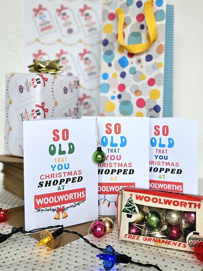 An image of three colourful Christmas cards that say so old you Christmas shopped at Woolworths with Christmas lights and baubles round them
