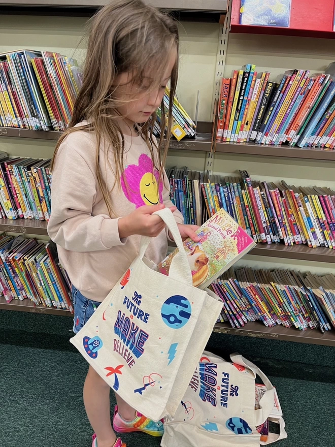 Girl puts library books into a small tote bag at the library
