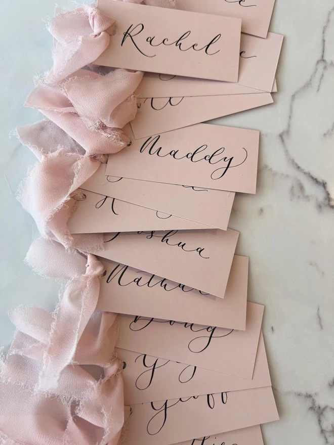 Personalised Calligraphy Wedding Pink Place Cards, pink wedding cards with pink ribbons grouped together. 