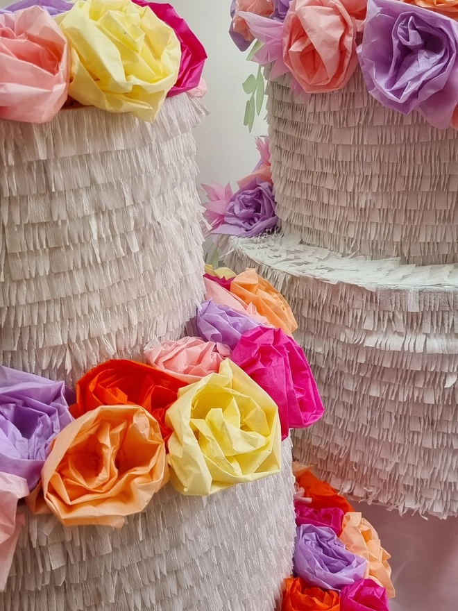 close up of tissue paper flowers on top of a wedding cake pinata