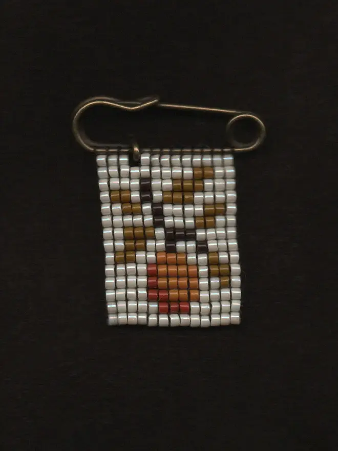 'flora viii' tiled beaded orange pin. a beaded pin badge with an orange tree branch on a pearl background.