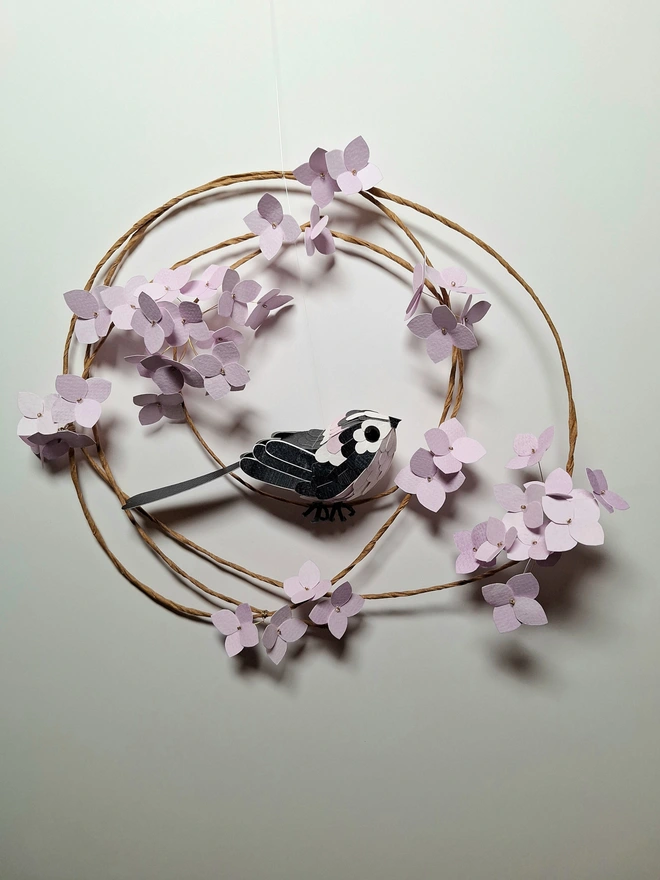 long tailed tit bird sculpture, perched on a wreath adorned with hydrangea blooms