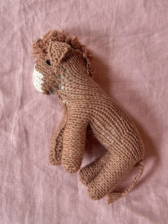 Hand Knitted Natural Dyed Wool And Alpaca Yarn Donkey Gift, placed on a pink tablecloth 