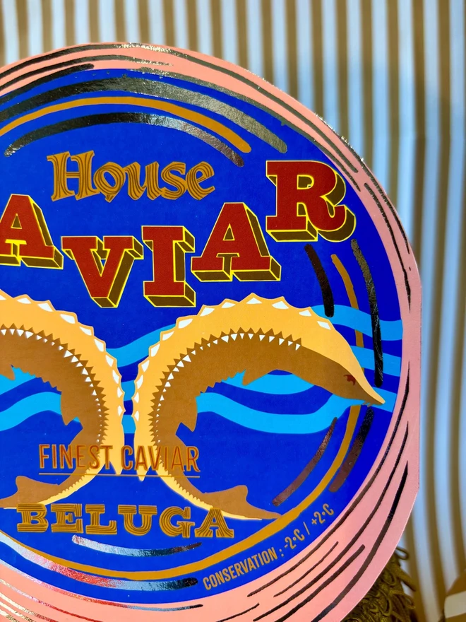 Caviar Tin Card, a colourful card sitting on a decorated display in front of a backdrop. 