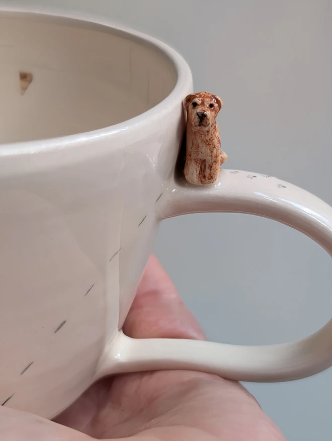 ceramic off white cup with a tiny Labrador dog on the handle and illustrated hearts
