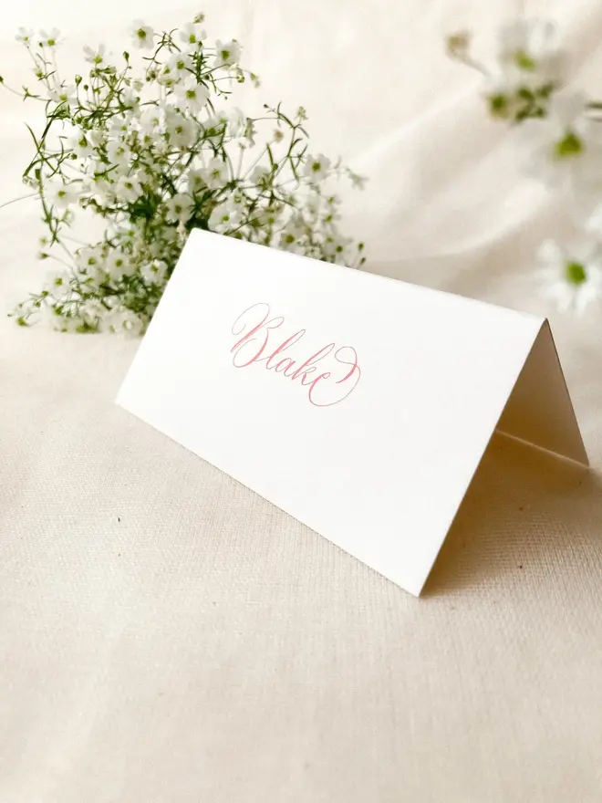 personalised calligraphy place cards. white place card with name in calligraphy pink ink.