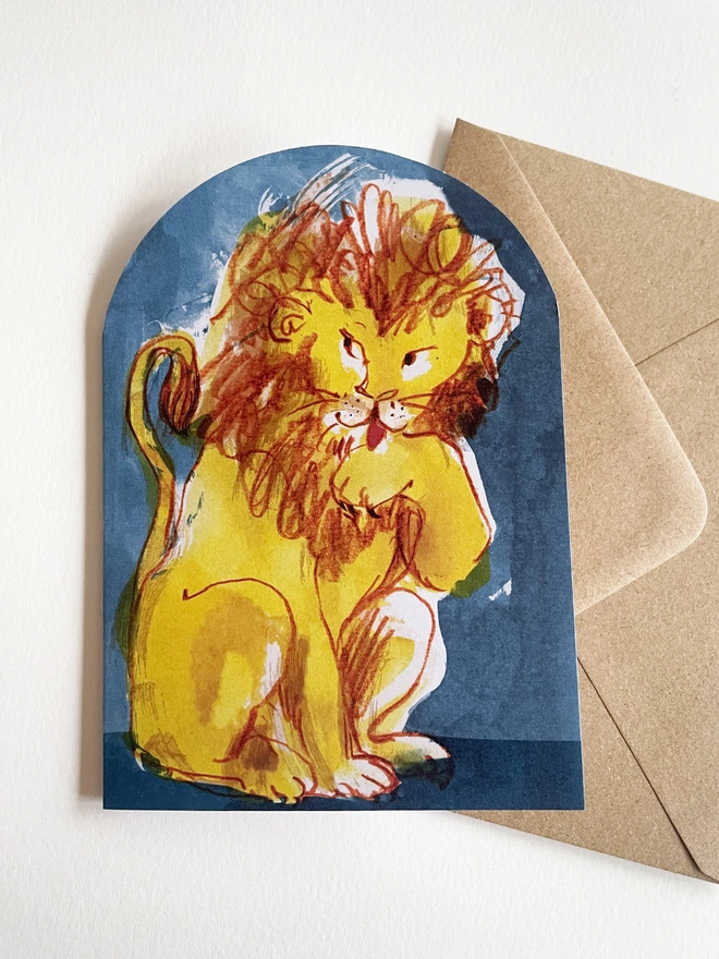 Esther Kent Lion illustrated arch-shaped greeting card, showing yellow and brown lion licking a paw, against a blue background.