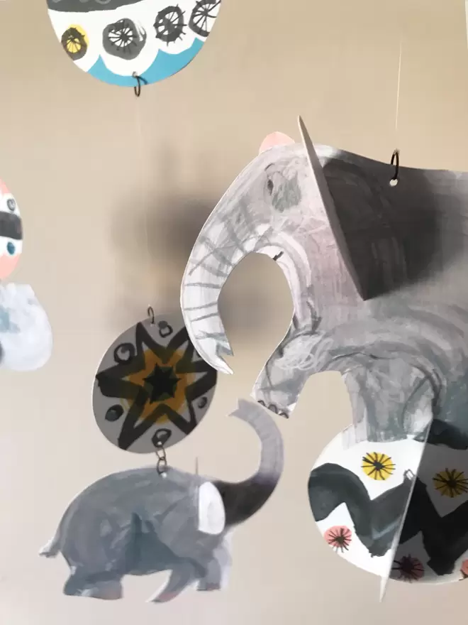 Esther Kent designed Circus Elephants mobile. Grey hand-drawn cut out elephants combined with mid-century circus patterns, casting shadows on a wall.
