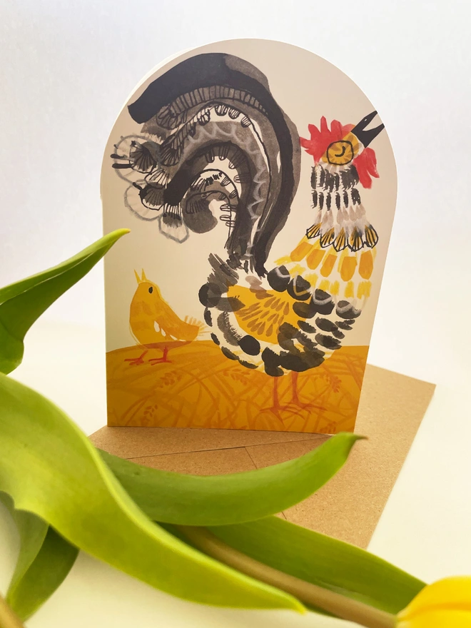 Esther Kent illustrated greeting card showing black, yellow and red stylised cockerel on an arch-shaped card