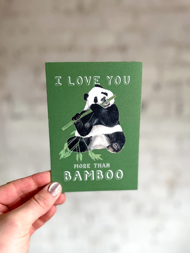 deep green card featuring a realistic illustration of a panda eating bamboo and the text "I Love You More Than Bamboo"