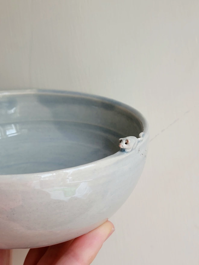 Grey glazed cat dish bowl with a small mouse attached on the egde of the rim held in a hand