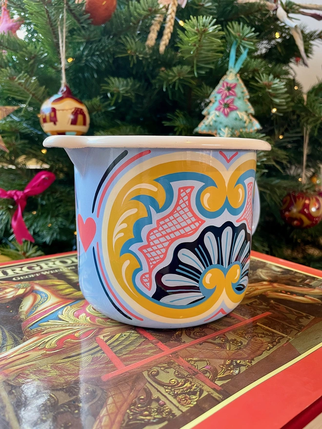 Blue enamel jug hand painted with a fairground design in blue, pink and yellow