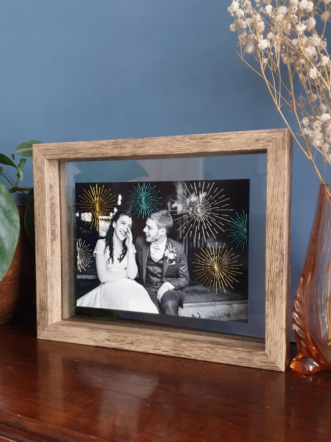 Wedding photo in B&W with hand embroidered sparkly fireworks in double glass frame on desk