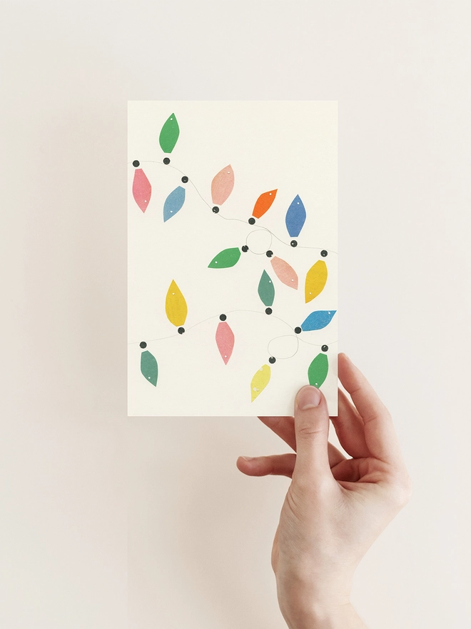 A minimal Christmas card featuring of pastel coloured fairy lights.
