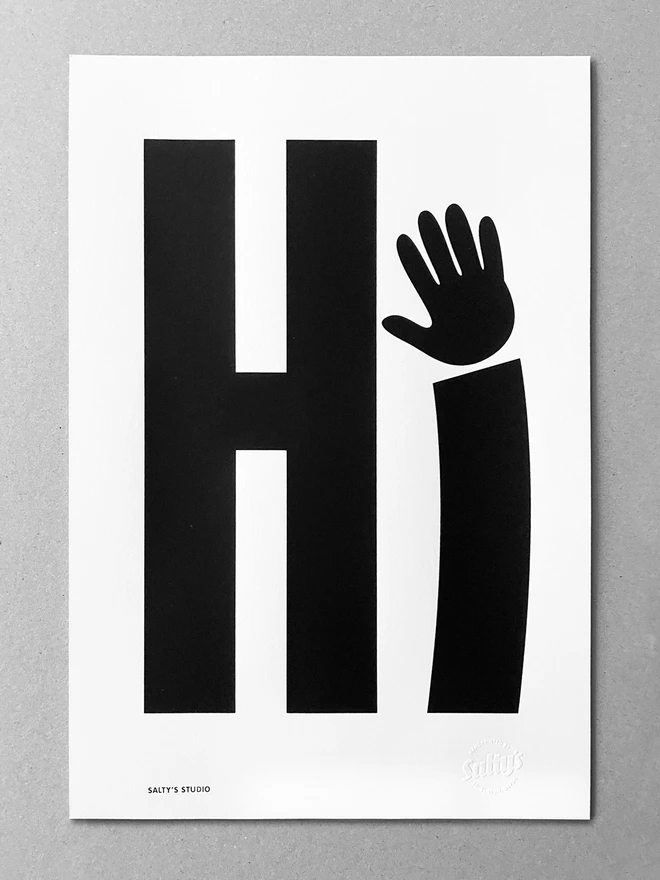 Full view of screenprinted Hi, with a waving hand as the i - sat on a grey background - showing detail of an embossed stamp saying Salty’s