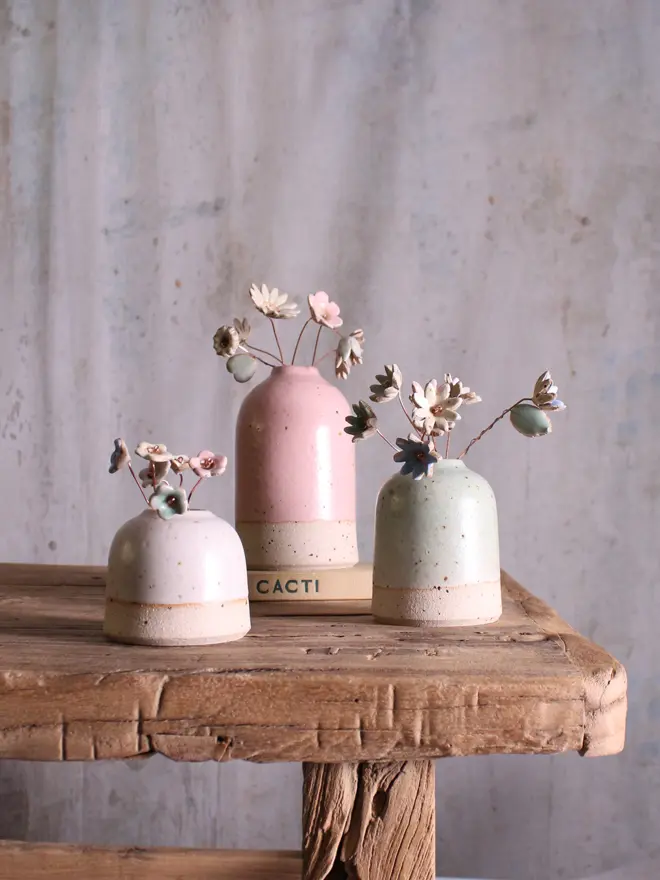 mini, small and medium vases filled with ceramic flower stems on wooden table