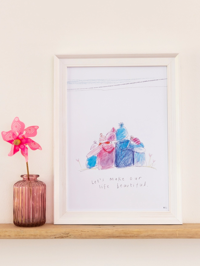 A sketchy muma print in a white frame next to a windmill in a vase