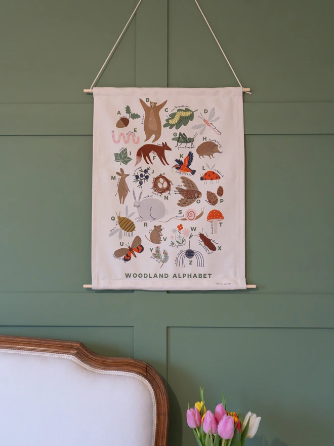 Woodland Alphabet Fabric Banner, against a green wall. 