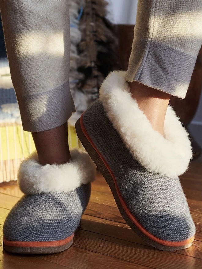 Women's Lambswool & Sheepskin Boot Slippers, a woman wearing a pair of boot slippers on a decorated floor. 