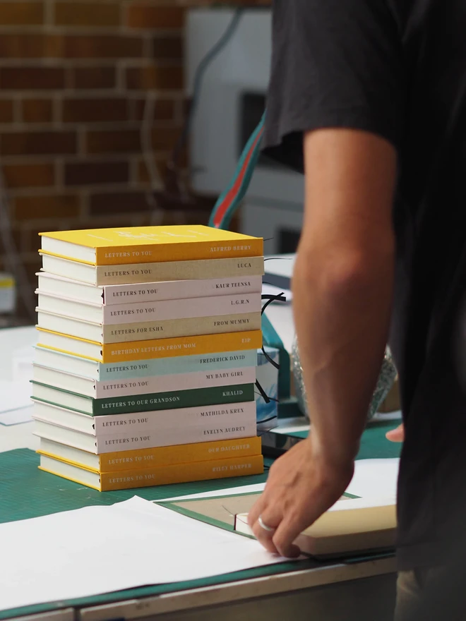 personalised letters to you hardcover book. a stack of hardcover journals being made at a workbench