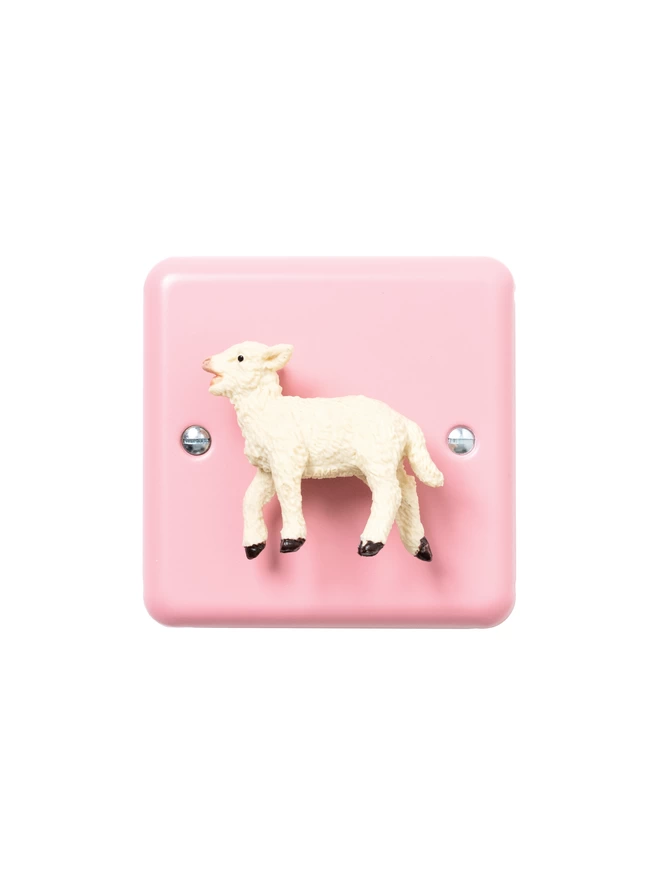 A pink nursery dimmer light switch with a lamb as the rotary knob. The light switch plate is pink and made of metal, epoxy coated steel. The lamb is made of plastic. The brand is Candy Queen Designs.
