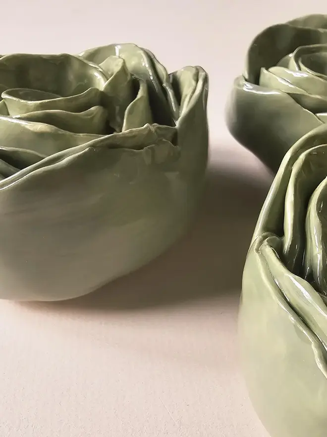 Handmade ceramic rose sculpture with a green glossy glaze, crafted in 3D and designed to hang on a wall