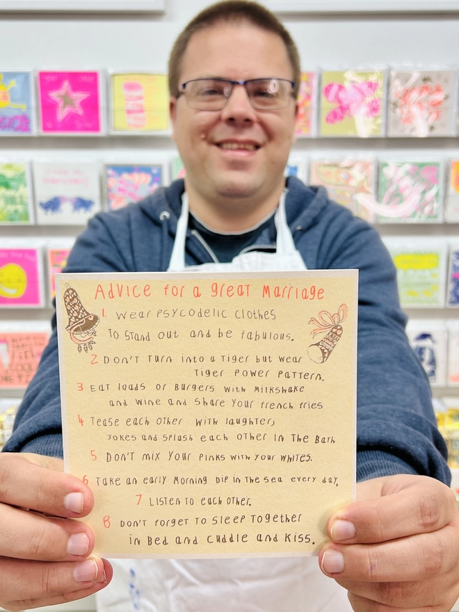 Artist holding a riso printed congratulations card featuring the words Advice for a Great Marriage 