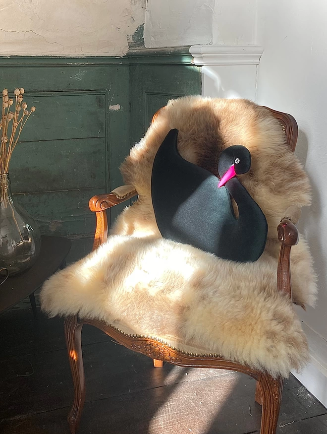 Green swan with pink beak on a vintage chair